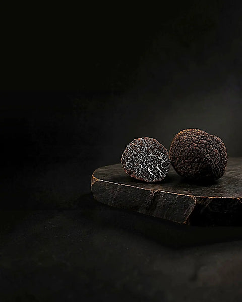 Fresh Black truffle – Tuber melanosporum – with its marbled interior displayed on dark stone